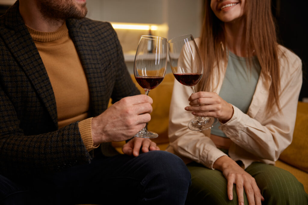 Spice Up Date Night - Romantic evening at home with close up view on clinking wine glasses